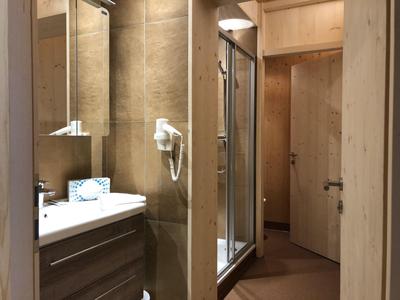 Compact bathroom with sink, mirror, hairdryer, and shower in wood decor