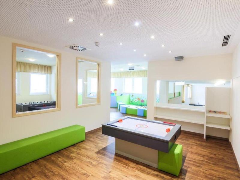 Bright, modern playroom with air hockey table, green bench, and large mirrors on the walls.