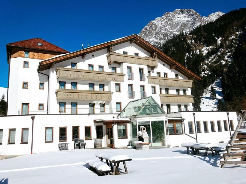 Verschneites Hotelgebäude vor Bergkulisse bei klarem Himmel