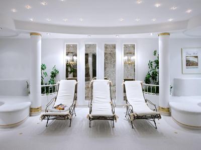 Sala blanca con tres tumbonas y elementos decorativos modernos en un hotel.