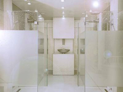 Baño moderno con paredes claras, paneles de vidrio y diseño minimalista.