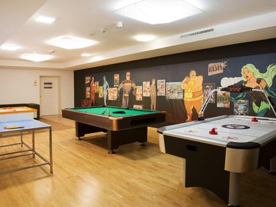 Sala de juegos con billar, air hockey y tenis de mesa en un hotel.
