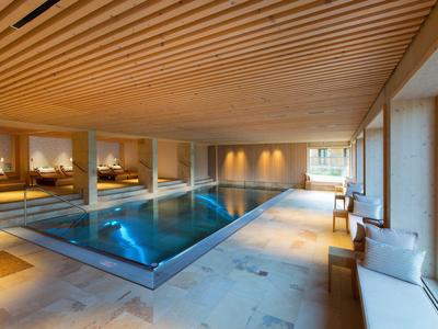 Piscine intérieure moderne avec plafond en bois et grandes fenêtres dans un hôtel.