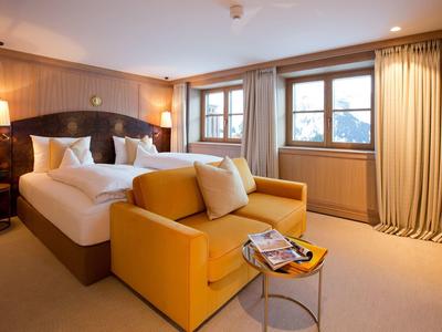 Habitación de hotel acogedora con cama doble, sofá amarillo y ventana con cortinas.