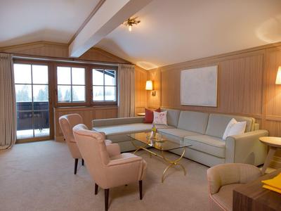 Cómoda habitación de hotel con zona de estar, sofá y ventana grande con cortinas.