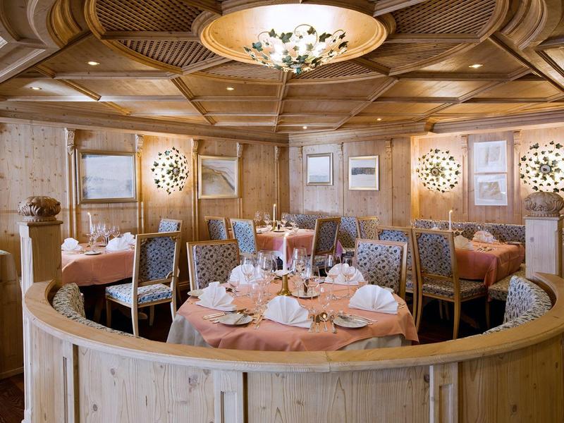 Área elegante de restaurante de hotel con mesas redondas, platos servidos y paneles de madera.