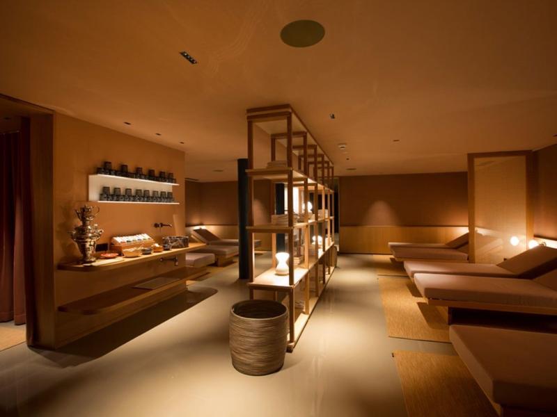Sala de spa cálida y con luz tenue con camillas y decoración relajante.