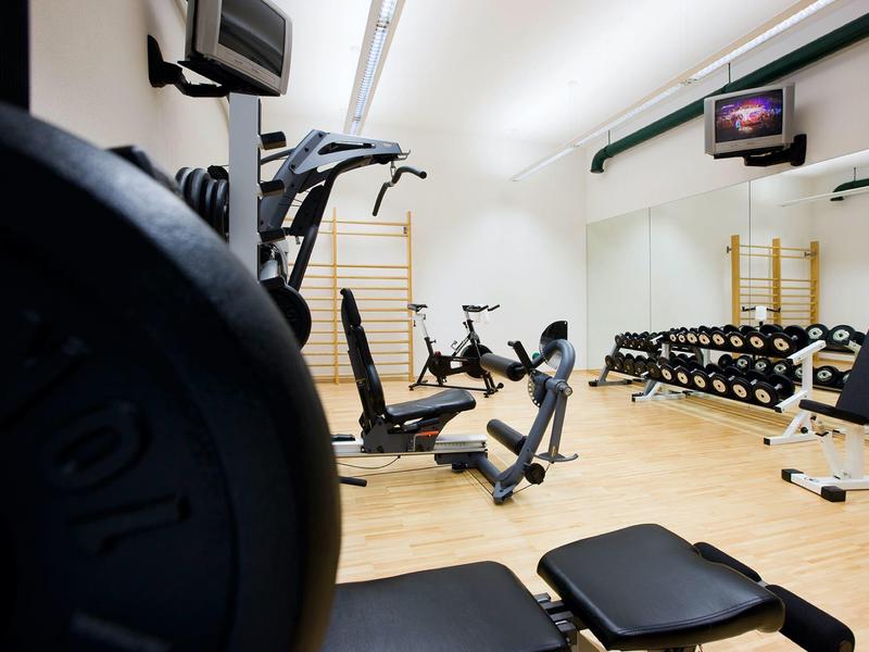 Gimnasio moderno con máquinas de ejercicio y pesas en una habitación luminosa.