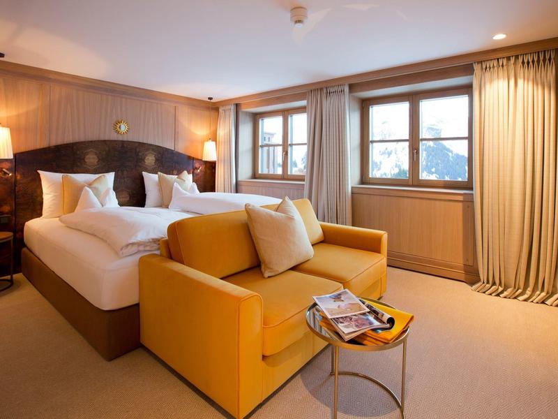 Habitación de hotel acogedora con cama doble, sofá amarillo y ventana con cortinas.