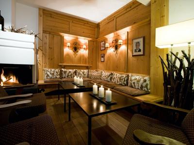 Coin salon confortable avec murs en bois, cheminée et bougies dans une pièce chaleureusement éclairée.