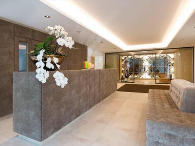 Moderne Rezeption mit grauem Empfangstresen, weißen Orchideen und gemütlichem Sitzbereich.