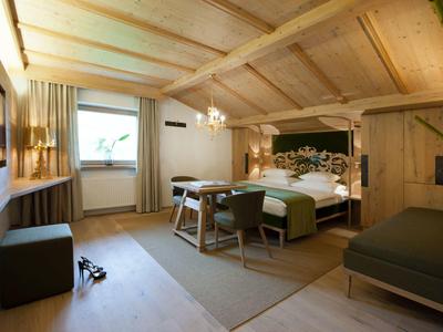 Gemütliches Schlafzimmer mit Holzwänden, Doppelbett, Stühlen, Fenster und weichem Teppich.