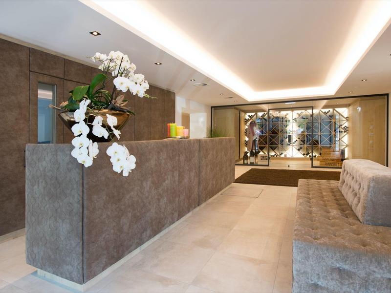 Moderne Rezeption mit grauem Empfangstresen, weißen Orchideen und gemütlichem Sitzbereich.