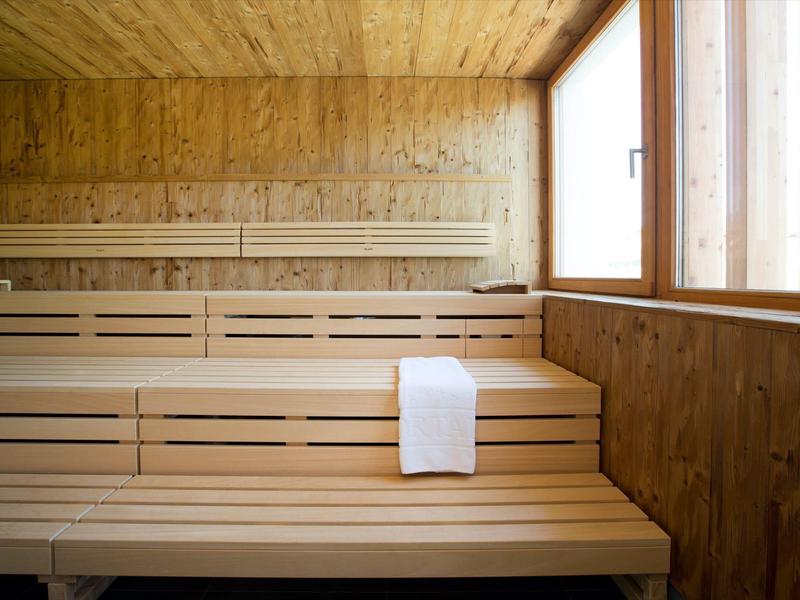 Helle Holzsauna mit mehrstufigen Sitzbänken und einem weißen Handtuch auf der mittleren Bank.