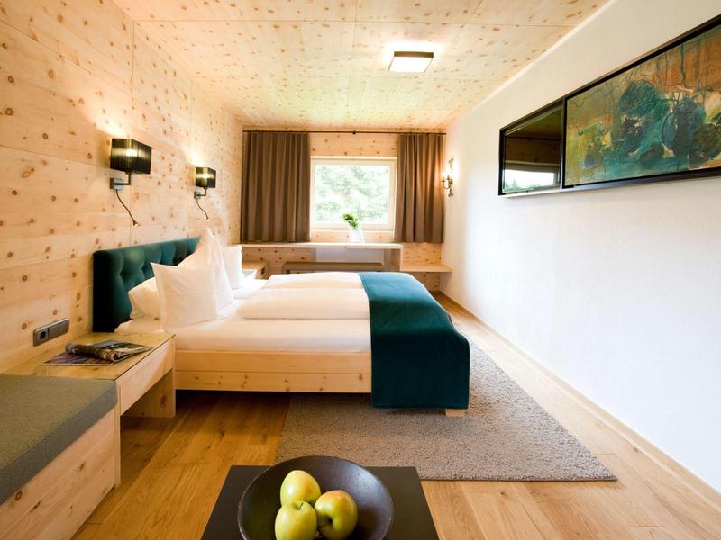 Helles, modernes Schlafzimmer mit Holzvertäfelung, Doppelbett, großem Fenster und grünem Dekor.