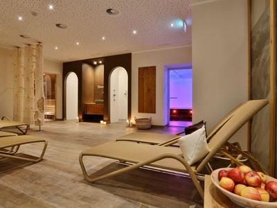 Ruheraum mit Liegestühlen, sanfter Beleuchtung und einem Korb mit roten Äpfeln im Vordergrund.