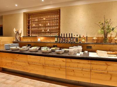 Buffet mit Holzschrank, verschiedenen Tellern, Flaschen und Blumenarrangements in warmem Licht.