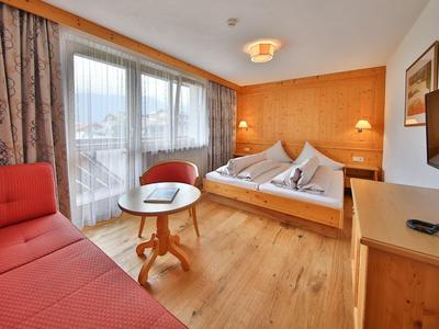 Gemütliches Hotelzimmer mit Doppelbett, Balkon und roter Couch