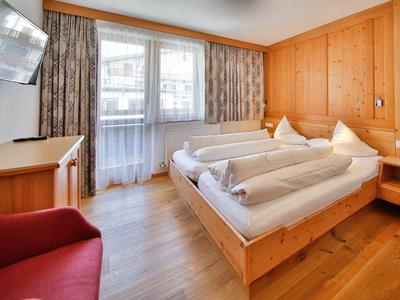 Gemütliches Hotelzimmer mit zwei Einzelbetten, Holzvertäfelung und großer Fensterfront.