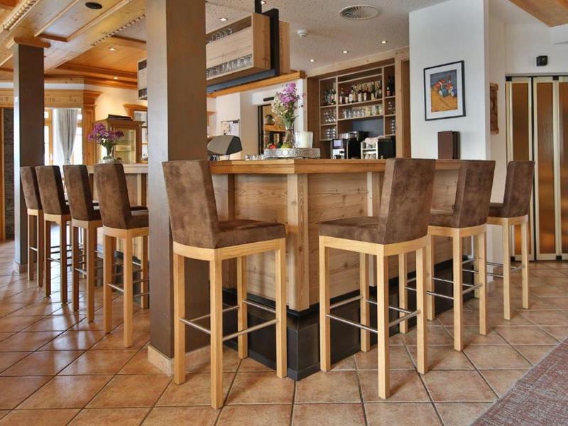 Moderner Holztresen mit sechs hohen Stühlen und Fliesenboden in hellem Gastraum.