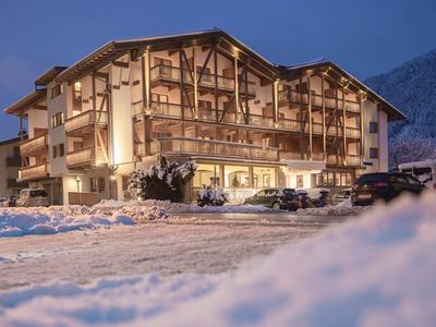 Gemütliches Hotel im Alpenstil bei Dämmerung und schneebedecktem Boden.