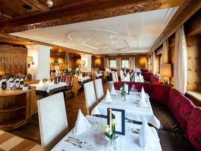 Elegantní restaurace s dřevěnými prvky a červenými čalouněnými lavicemi u oken