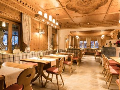 Útulná tradiční restaurace s dřevěným nábytkem a složitě zdobeným stropem.