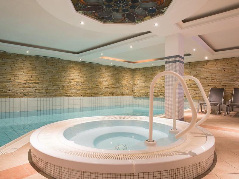 Ein moderner Wellnessbereich mit rundem Whirlpool und angrenzendem rechteckigem Pool.