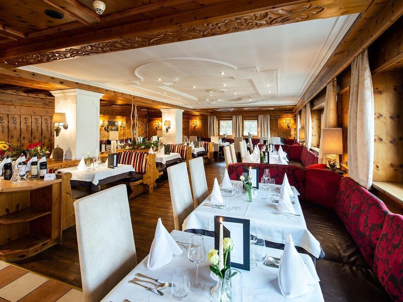 Gemütliches Restaurant mit Holzbalken, weißen Tischdecken und roten Sitzbänken am Fenster.