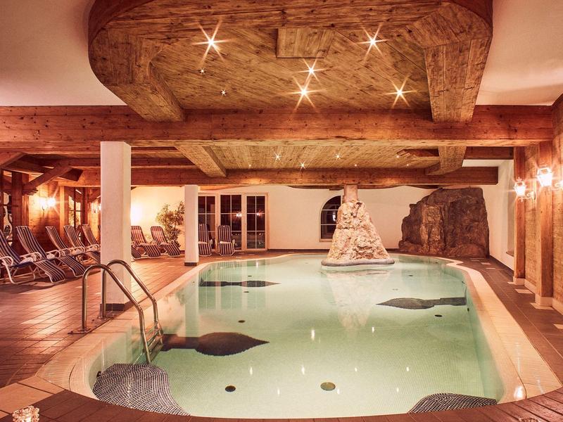 Innenpool in rustikalem Raum mit Holzbalken, Kerzenlicht und stilvollem Dekor auf einer Säule.