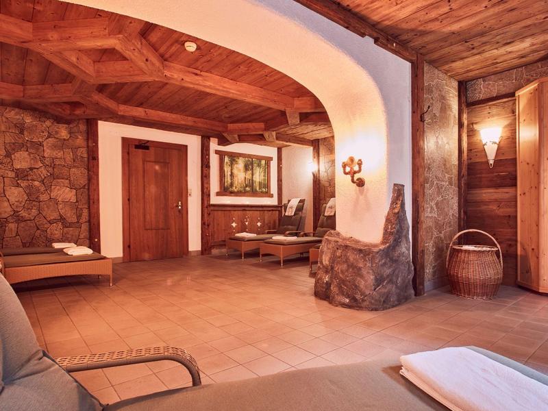 Gemütlicher Raum mit holzverkleideter Decke, steinernen Wänden und weichem Sofa im Vordergrund.