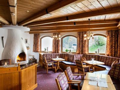 Przytulny salon hotelowy z kominkiem, drewnianym sufitem i tapicerowanymi fotelami przy dużych oknach.