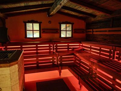 Holzsauna mit roten LED-Leuchten unter den Bänken und zwei kleinen Fenstern.