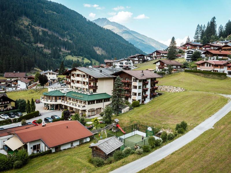 Bergdorf mit Häusern und Wiesen in einem grünen Tal unter blauem Himmel.