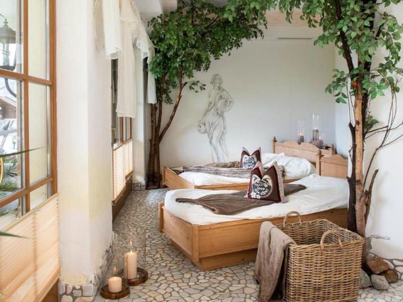 Gemütliches Schlafzimmer mit Holzbetten, Pflanzen, Kamin und Naturdekor in hellem Raum.