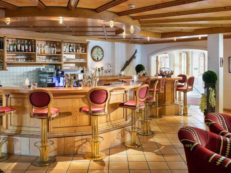 Gemütliche Bar mit Holztheke, roten Barhockern, Holzdecke und warmem Licht.