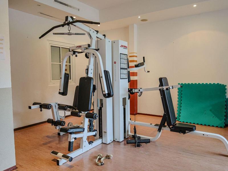 Moderner Fitnessraum mit multifunktionalem Trainingsgerät und Hantel auf Holzboden.