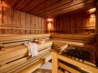Gemütliche Sauna mit mehrstufigen Holzliegen, warmem Licht und einem Handtuch.