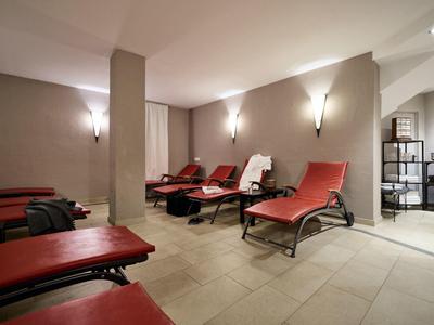 Ruheraum mit roten Liegen, beiger Wandgestaltung und weichem Bodenbelag in modernem Spa-Bereich.