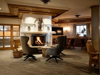 Acogedora zona de salón del hotel con chimenea, sillones y muebles de madera con luz cálida.