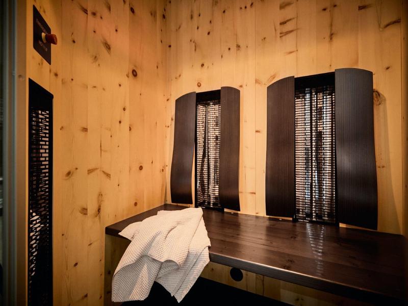 Ein Holzzimmer mit zwei schwarzen Saunaaufgussbehältern und einem weißen Handtuch auf dem Holztisch.