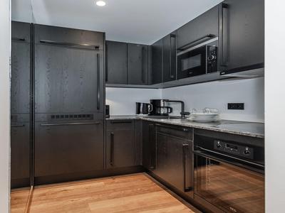 Moderne schwarze Küche mit Holzfußboden, Einbaumikrowelle, Kaffeemaschine und Spülmaschine.