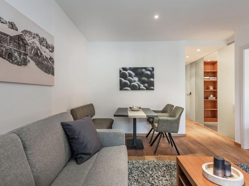 Helles Wohnzimmer mit grauem Sofa, dunklem Tisch, Stühlen und moderner Fotokunst an der Wand.