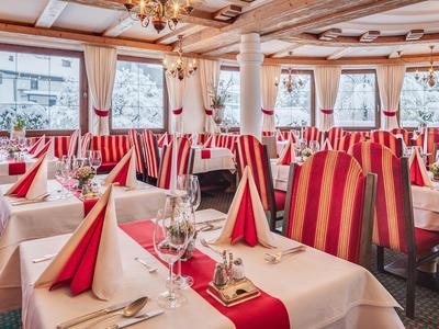 Elegantes Restaurant mit rot gestreiften Sesseln und weiß gedeckten Tischen mit roten Servietten.
