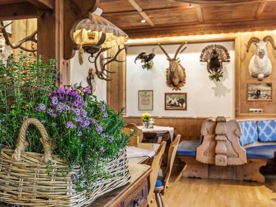 Gemütlicher Gastraum mit Holzmöbeln, Blumendekoration und Jagdtrophäen an den Wänden.