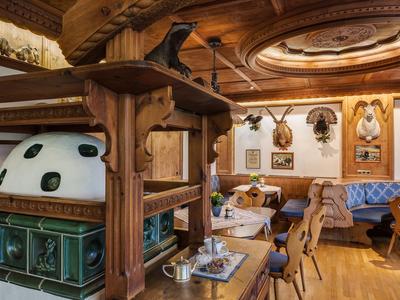 Gemütliche Stube mit holzverkleideten Wänden, Kachelofen und rustikalen Holzmöbeln.