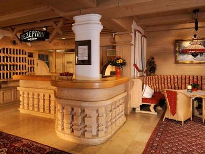 Gemütliche Hotellobby mit Holzmöbeln, Rezeption und Sitzbereich mit gepolsterten Bänken.