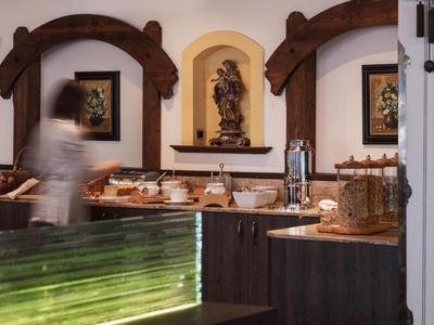 Innenraum mit rustikaler Holzbalkendekoration, Buffet mit Speisen, unscharfe Person in Bewegung.