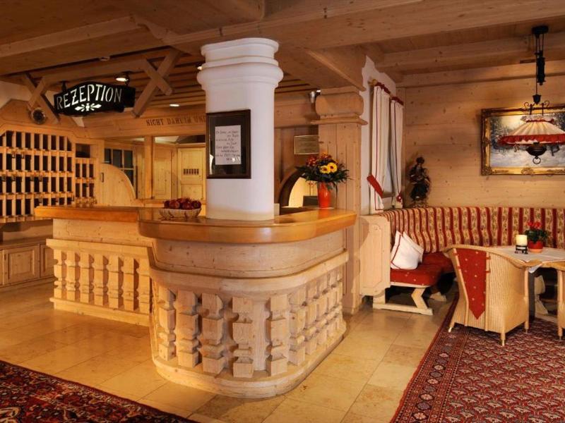 Helles, gemütliches Hotel-Foyer mit Holztheke, Sitzgruppen und warmen Holztönen.