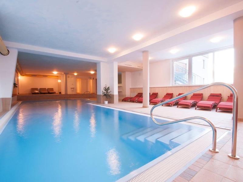 Hell erleuchteter Innenpoolbereich mit Liegestühlen und großen Fenstern